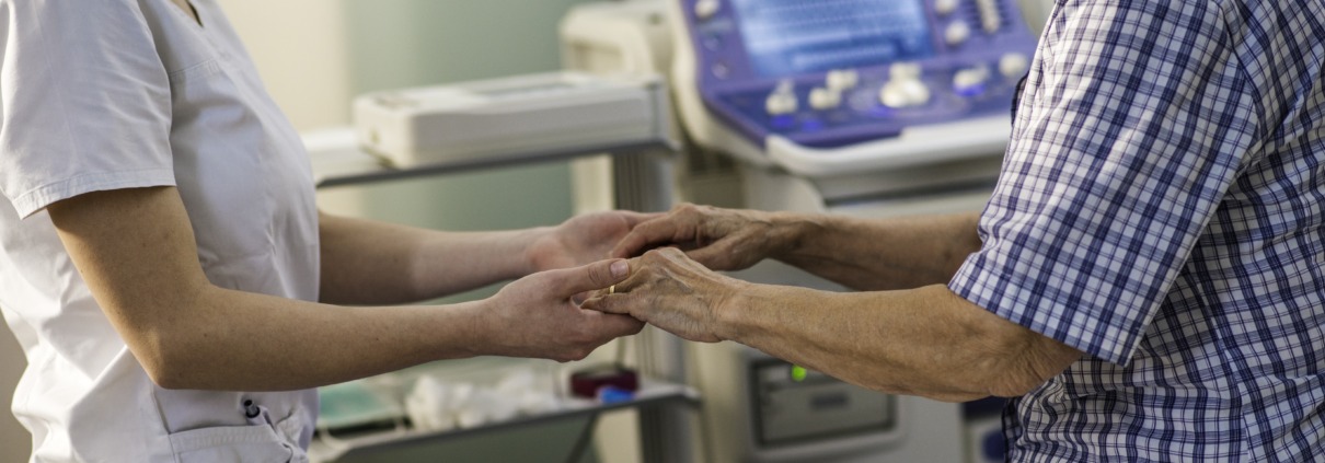 Pflegeperson oder Ärztin hält alten Menschen an den Händen